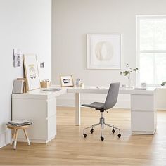 a white desk and chair in a room with wood floors, framed pictures on the wall