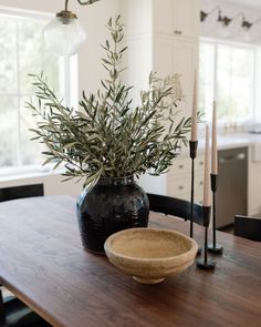 a wooden table topped with a black vase filled with greenery