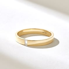 a yellow gold ring with a single diamond in the center on a white tablecloth