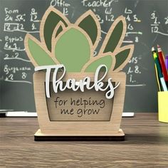 there is a wooden sign that says thanks for helping me grow on the desk in front of a chalkboard