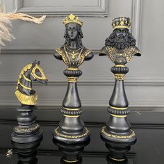 three black and gold chess pieces sitting next to each other on top of a table