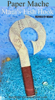 a paper mache that is sitting in some blue grass with the words mau's fish hook on it