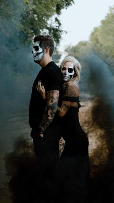 a man and woman in skeleton makeup standing next to each other on a dirt road