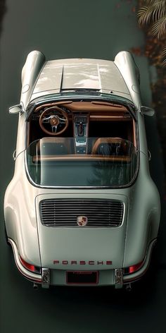 an overhead view of a white sports car with its hood up and the dashboard showing