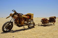 an old motorcycle is parked in the desert with bags strapped to it's back