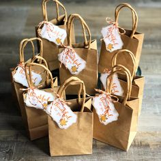 small brown paper bags with white and orange designs on them sitting on a wooden table