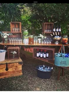 an outdoor bar is set up with bottles and buckets on the table for drinks