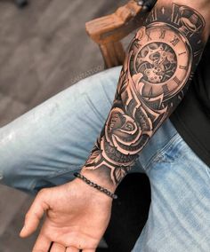 a man's arm with a clock tattoo on it and his hand in the air