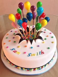 a birthday cake decorated with colorful balloons and the name smith on it's frosting