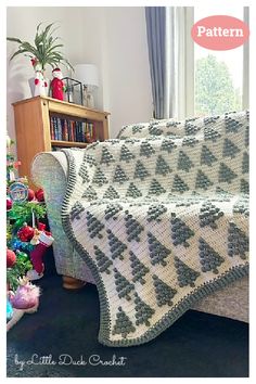 a crocheted blanket sitting on top of a couch next to a christmas tree