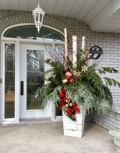 a planter filled with greenery and candles on the front porch