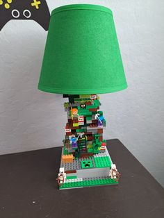 a lamp made out of legos and a green shade on a table with a video game controller in the background