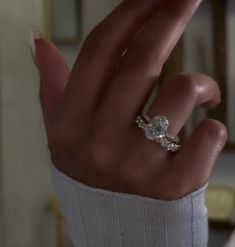 a woman's hand with a diamond ring on top of her finger, in front of a mirror