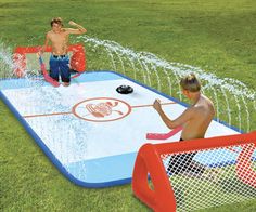 two kids playing in an inflatable hockey rink with water sprinkles