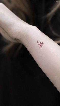 a woman's arm with a small red bird tattoo on it