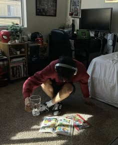 a man sitting on the floor in front of a tv with his head down while reading a book