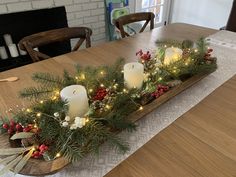 a wooden table topped with candles and greenery