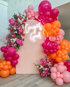 an arrangement of balloons and flowers on the floor next to a sign that says happy birthday