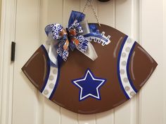 a football shaped door hanger with a star on the side and a bow hanging from it