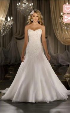 a woman in a white wedding dress standing on a stage with chandeliers behind her