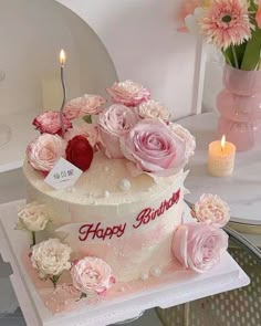 a birthday cake decorated with pink flowers and candles