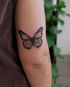 a black and white butterfly tattoo on the arm