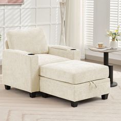 a white chair and ottoman in a living room with flowers on the side table next to it