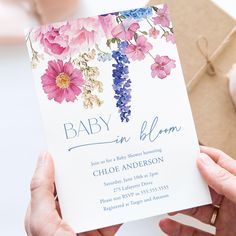 a person holding up a baby in bloom card next to a package with flowers on it