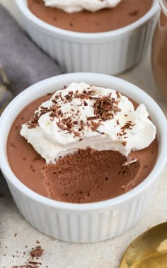 two white bowls filled with chocolate pudding and whipped cream