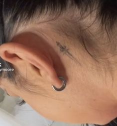 a woman with a small cross tattoo on her ear