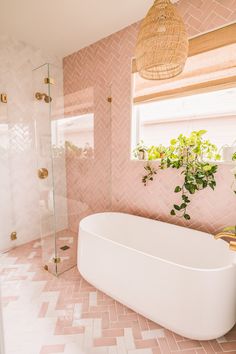 a white bath tub sitting next to a window with potted plants on top of it