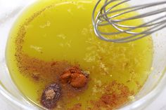 a whisk in a bowl filled with yellow liquid and spices