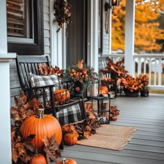 a porch decorated for fall with pumpkins and other decorations