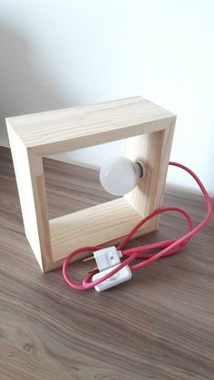 a wooden object with wires attached to it on the floor next to a white wall