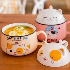 three bowls with cats on them sitting on a table next to one bowl filled with soup