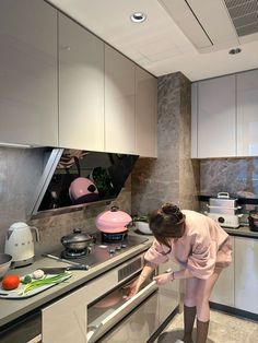 a woman bending over to look inside an oven