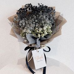 a bouquet of flowers is wrapped in brown paper and tied with a black ribbon on top