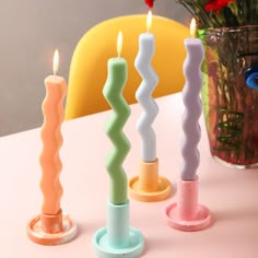 three candles sitting on top of a table next to a vase with flowers in it