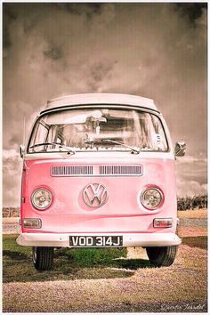 an old vw bus is parked on the grass in front of a cloudy sky