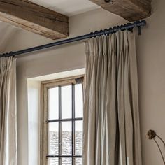 an open window with curtains hanging from it's sides and a wooden beam in the middle