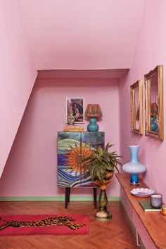 a living room with pink walls and wooden flooring, vases on the table