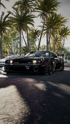 a black sports car driving down a street next to palm trees