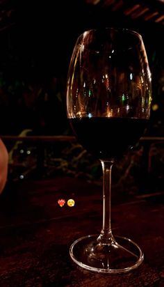 a glass of wine sitting on top of a table next to a person's hand