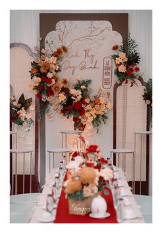 a long table with white chairs and red flowers on the wall behind it is set up for a formal function