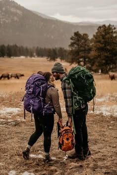 two people with backpacks are walking in the snow