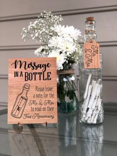 a message in a bottle next to a vase with white flowers and an empty card