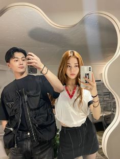 a man taking a selfie in front of a mirror with a woman standing next to him