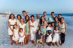 a large group of people standing on top of a sandy beach next to the ocean