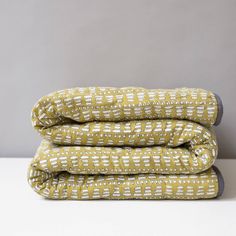 three yellow and white sheets stacked on top of each other in front of a gray wall