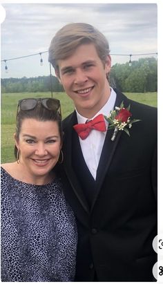 a man in a tuxedo standing next to a woman wearing a red bow tie